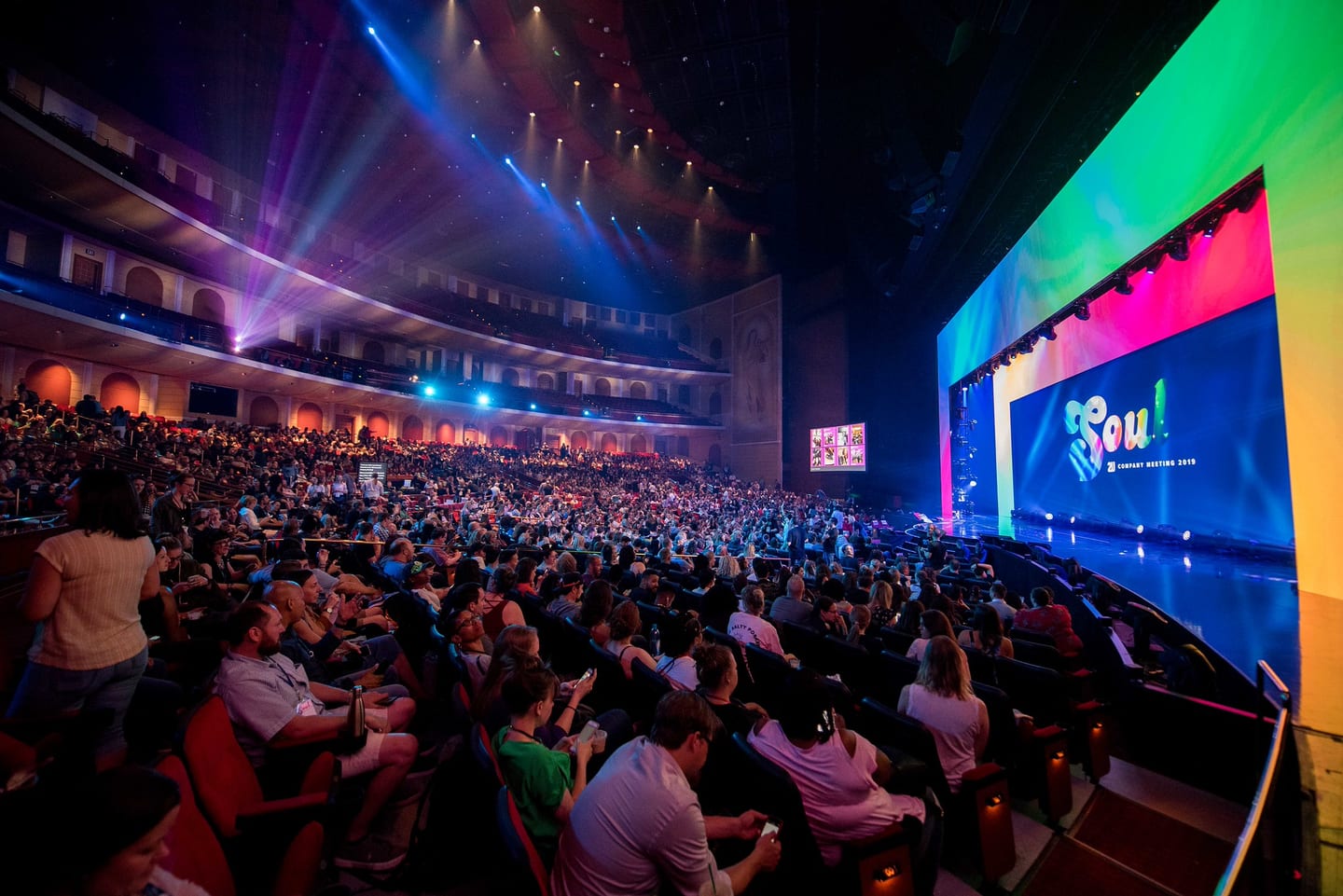 A packed Colosseum at Caesars Palace seen from the side, the full-width SOUL stage screen lighting the theatre during the 2U company meeting