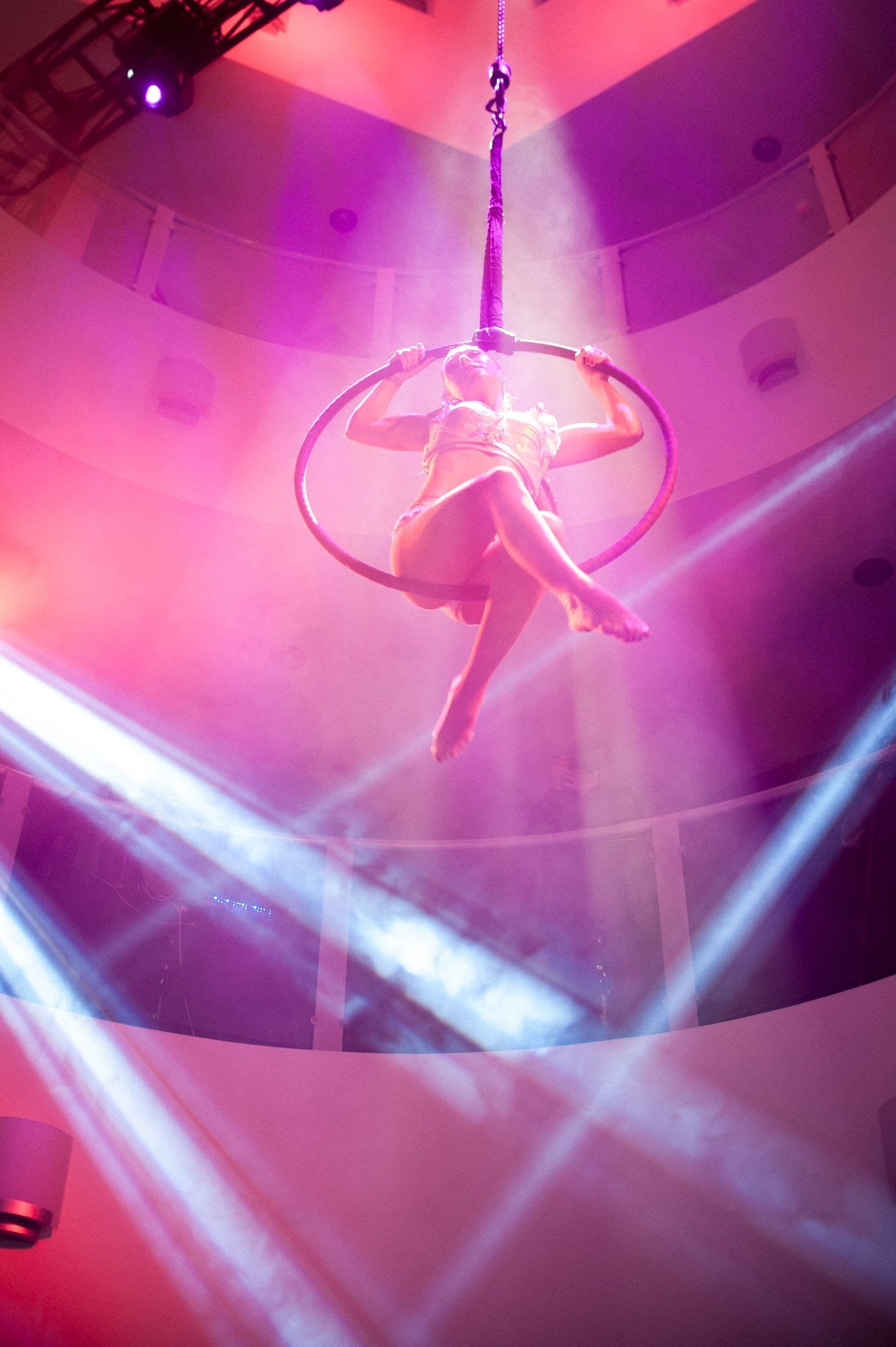 Aerial performer under purple stage lighting at an event
