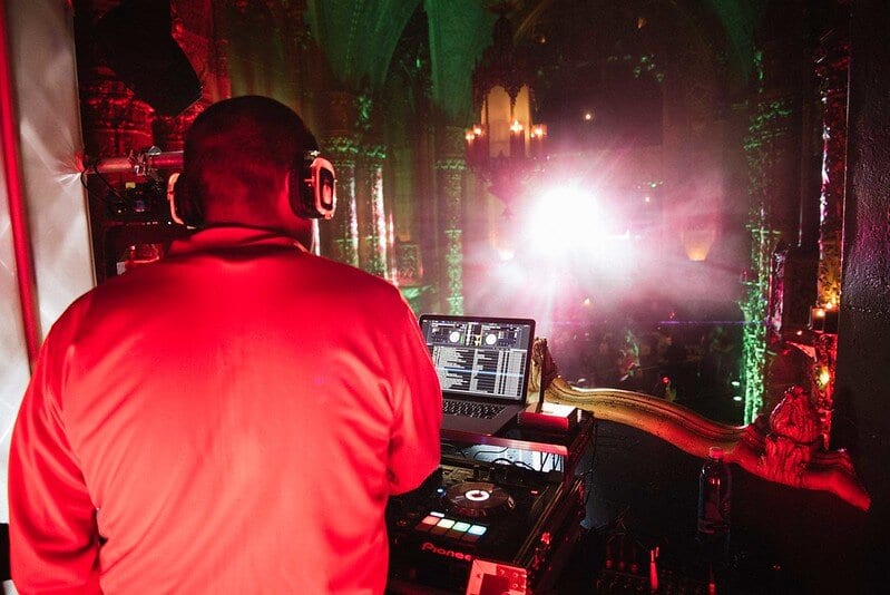 DJ performing at turntables in red light at an after-party