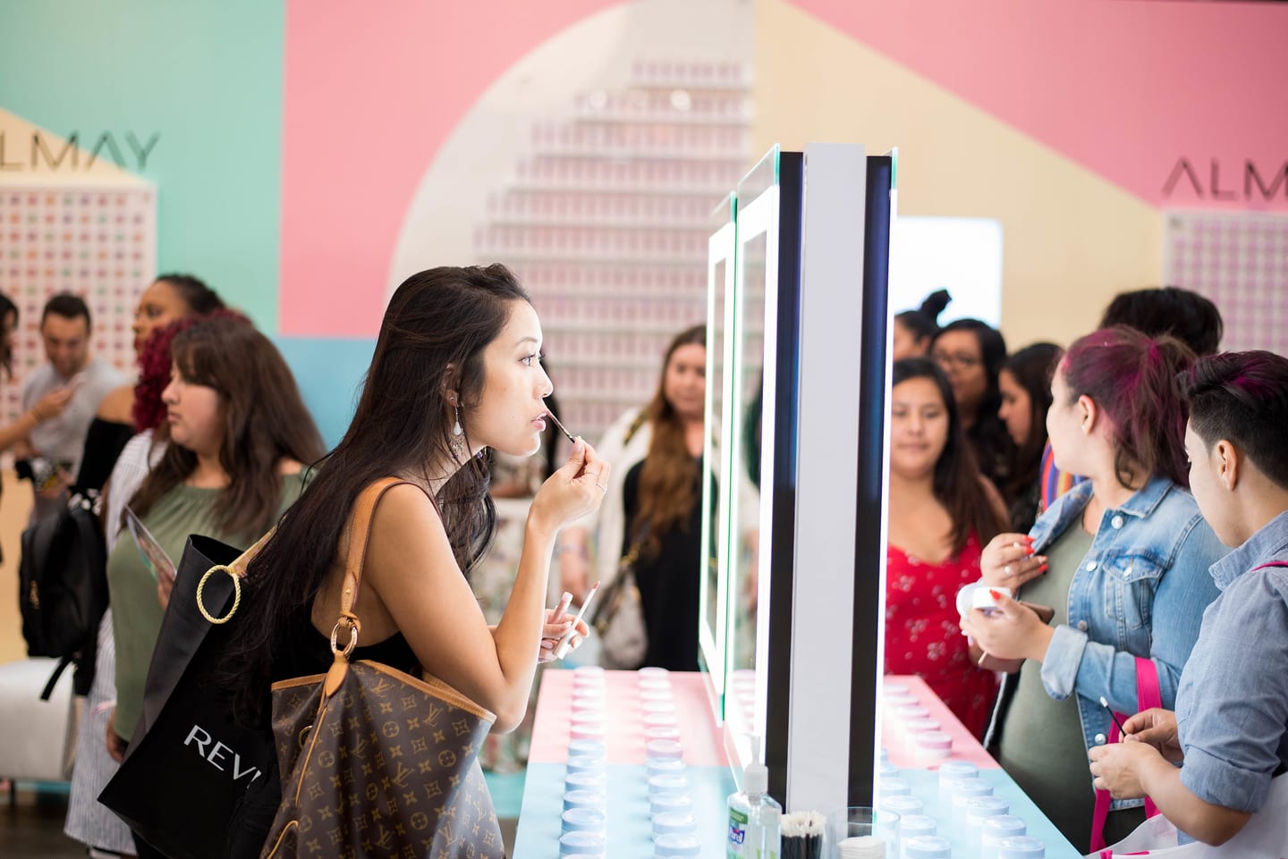 Guests testing lipstick at the mirrored counter of the Almay Cosmic Collection beauty activation