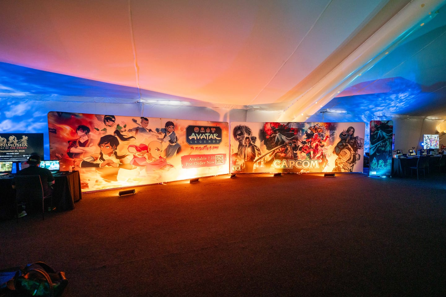 A backlit mural wall in the Anime Expo 2026 gaming tent showing Avatar Legends: The Fighting Game and Capcom titles including Onimusha