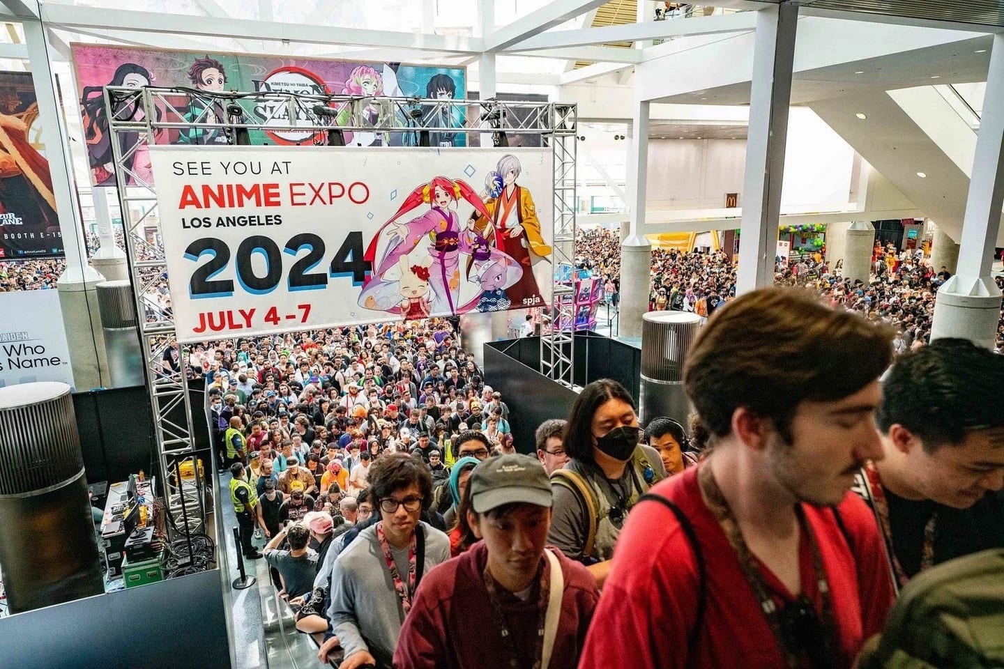 Crowds riding the escalator beneath the Anime Expo Los Angeles banner inside the Los Angeles Convention Center