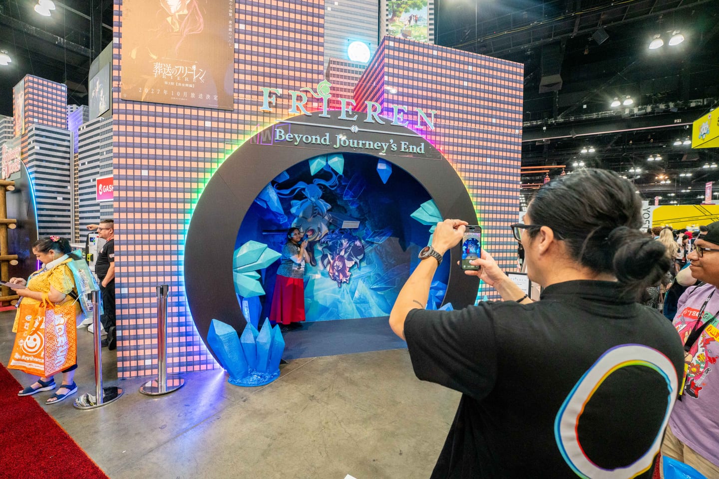 An attendee posing inside the blue crystal archway of the Frieren: Beyond Journey’s End booth at Anime Expo 2026