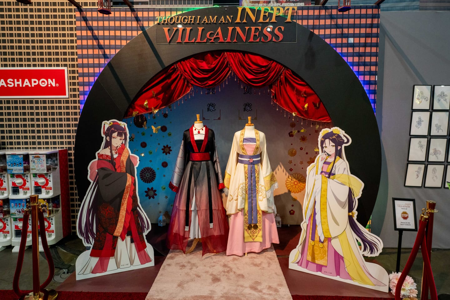 Costume displays and character standees under a red proscenium arch at the “I’m the Villainess, So I’m Taming the Final Boss” booth at Anime Expo 2026