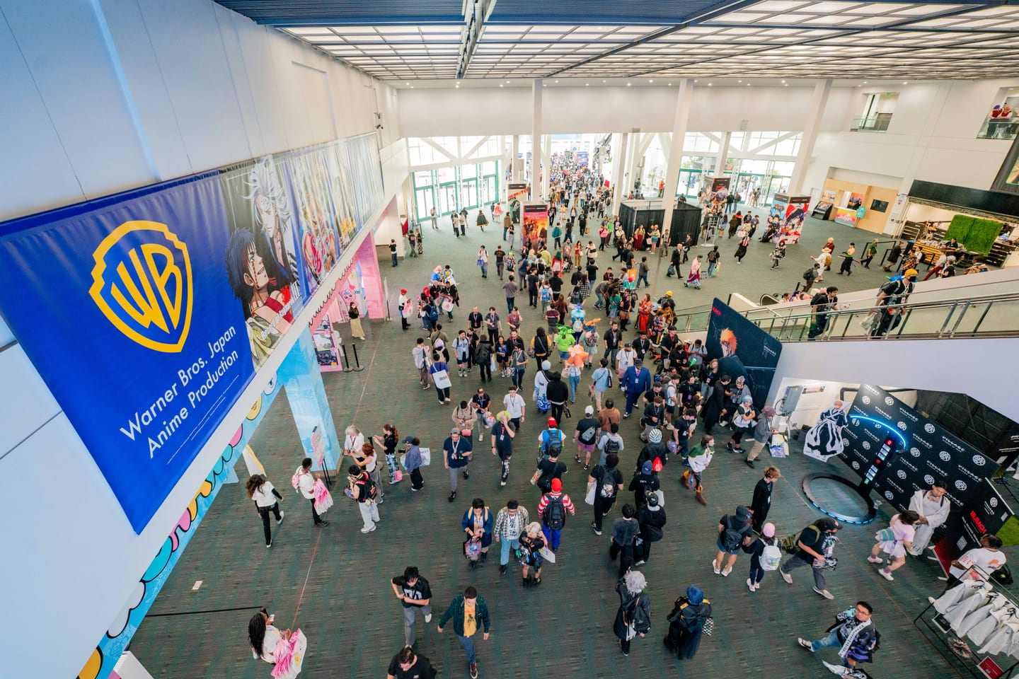 An overhead view of the Warner Bros. Anime booth and its shield logo on the Anime Expo 2026 exhibit floor with crowds moving through
