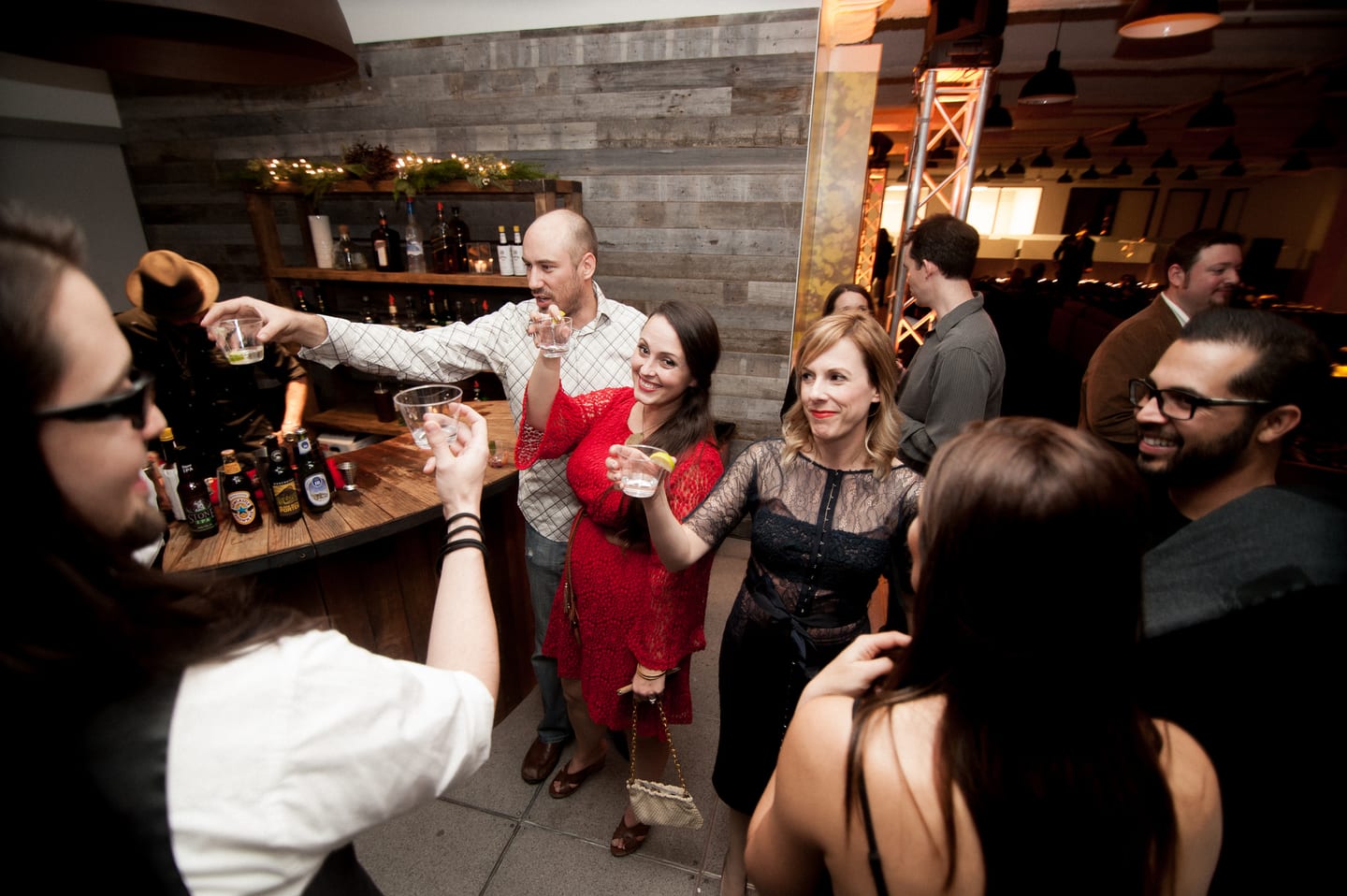 Group of guests raising glasses in a toast at a bar