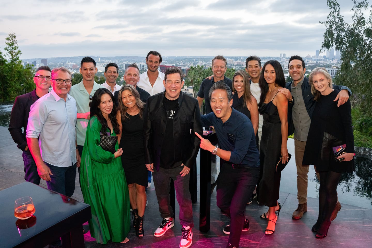 A group of well-dressed guests posing at a rooftop birthday party with a city view in Los Angeles