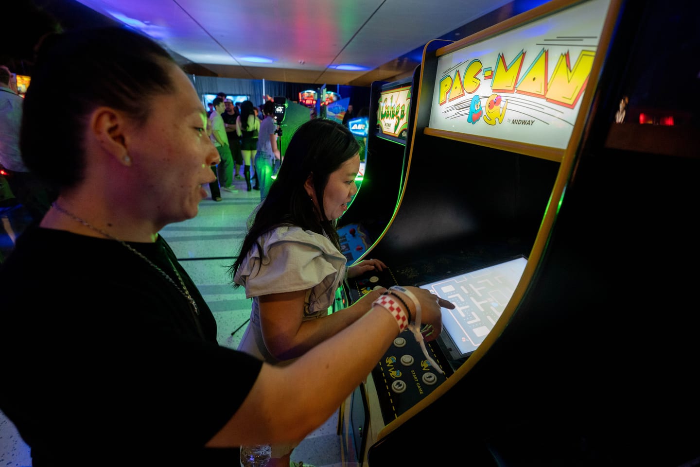 Two guests playing a Pac-Man arcade cabinet