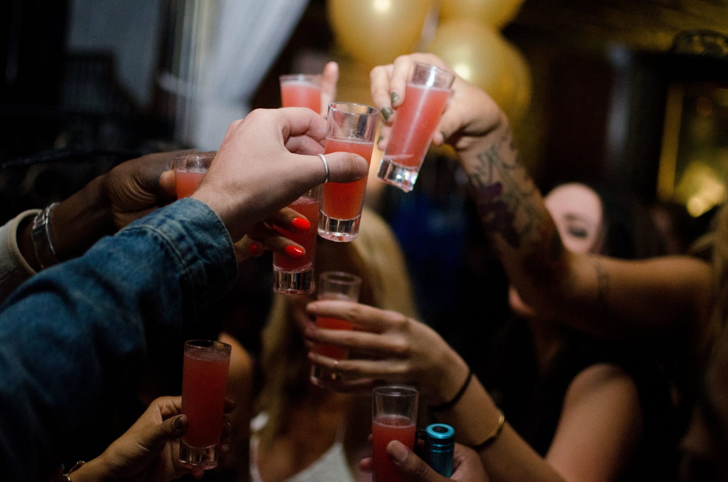 Hands raising glasses together in a toast at a party