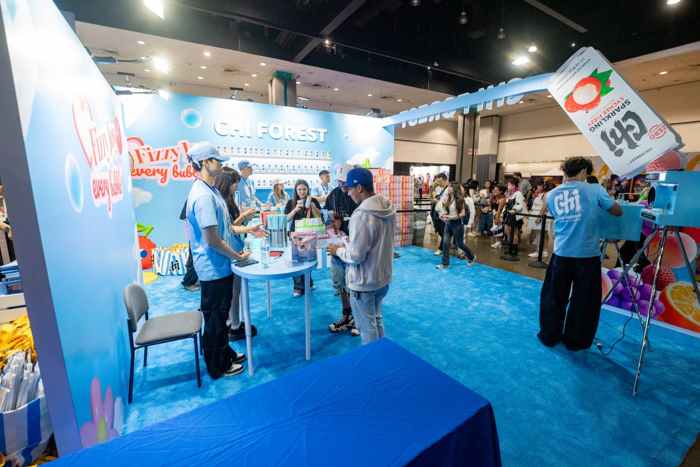 The blue Chi Forest sparkling water booth at KCON LA 2025 with a Fizzy In Every Bubble backdrop and staff sampling cans to attendees