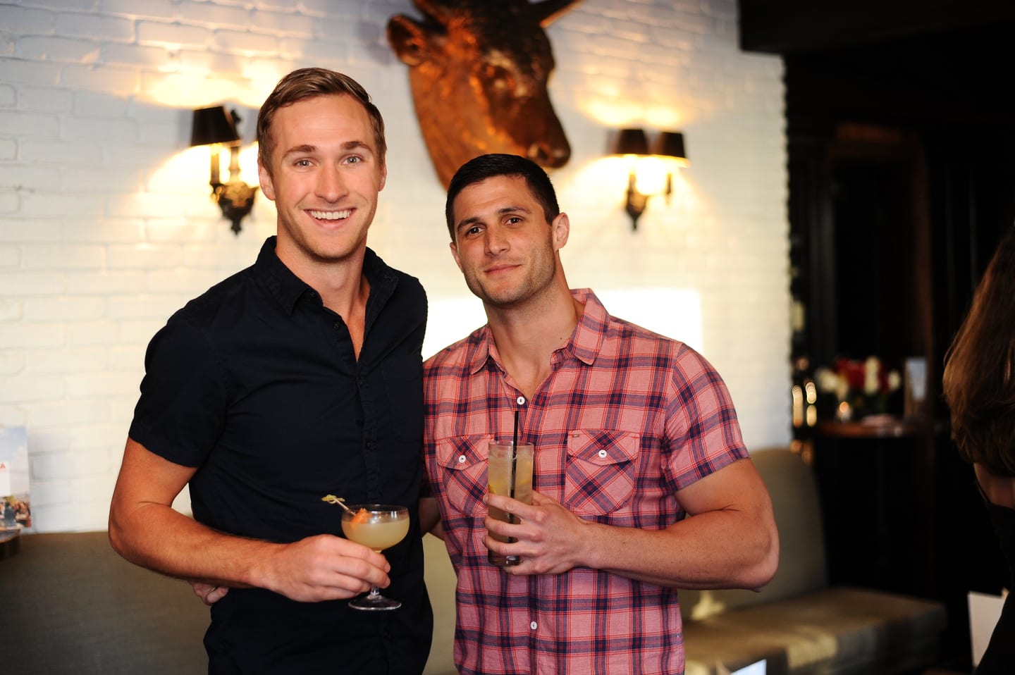 Two guests with craft cocktails at a bar during a party