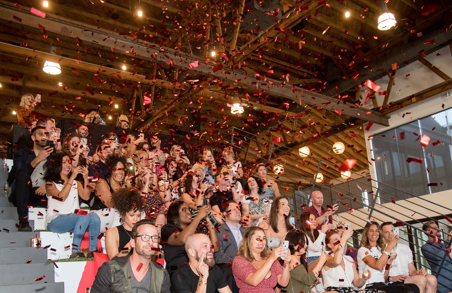 Red and white confetti falling over a packed crowd looking up at a brand party