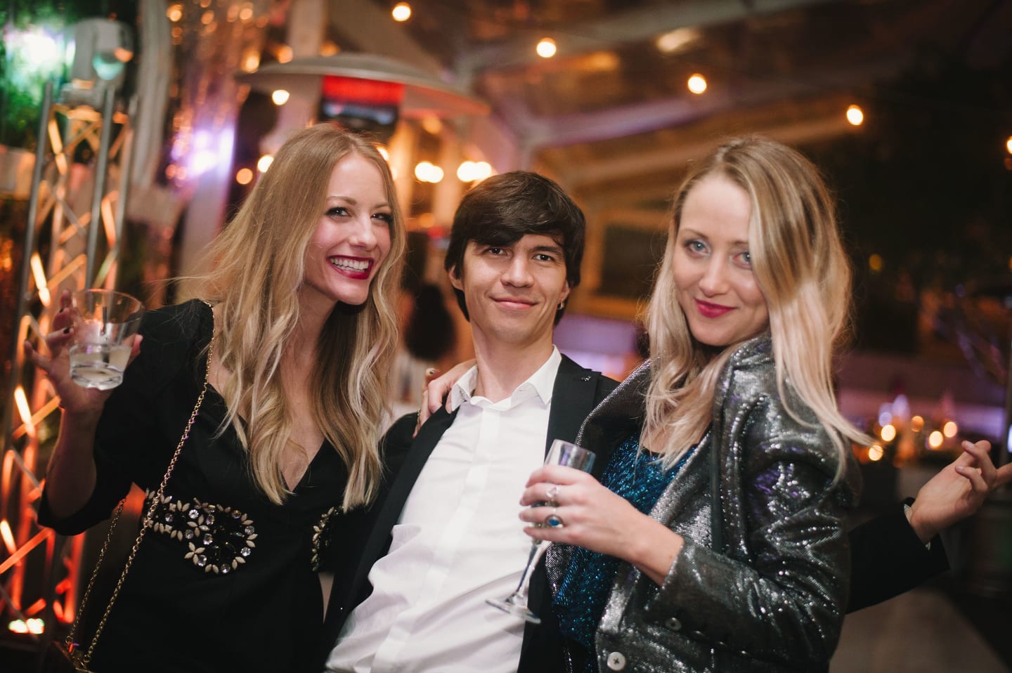 Three guests posing on a couch at an upscale lounge party