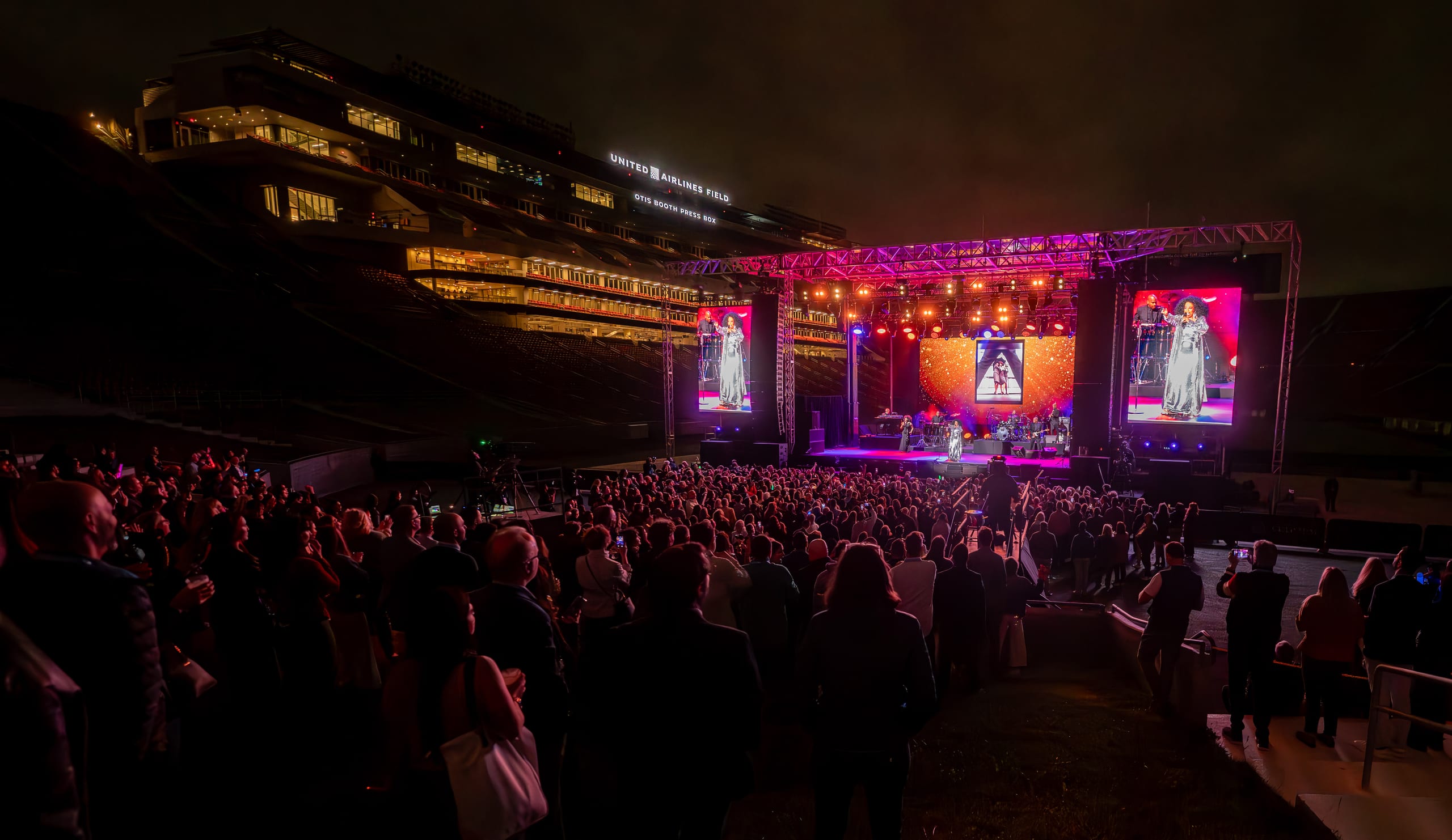 Diana Ross performing on a lit stage at the Los Angeles Memorial Coliseum before a large IPW opening-night crowd