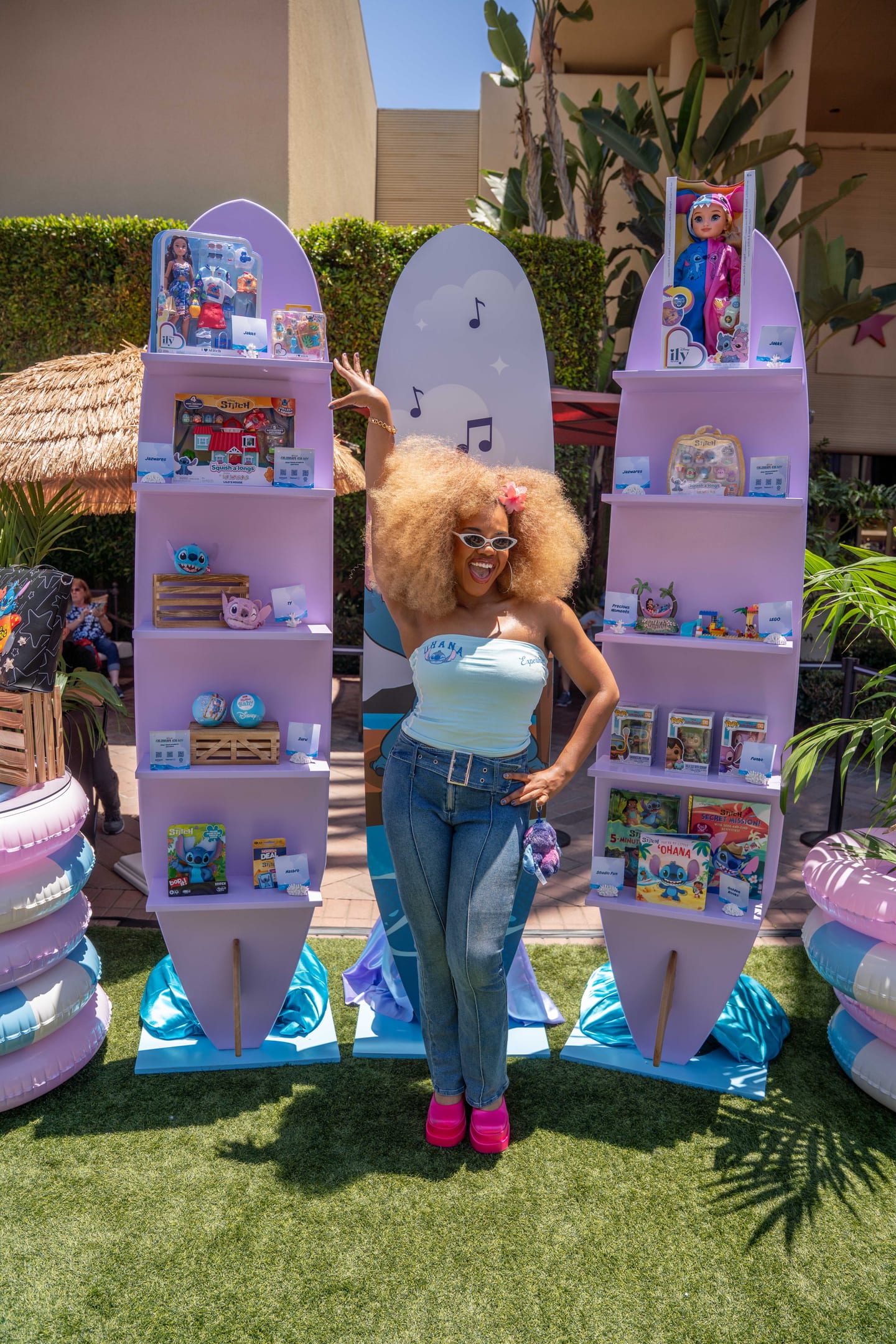 Dara Reneé posing between surfboard-shaped displays of Disney Stitch merchandise at Stitch’s 626 Day Beach Bash at Fashion Island in Newport Beach