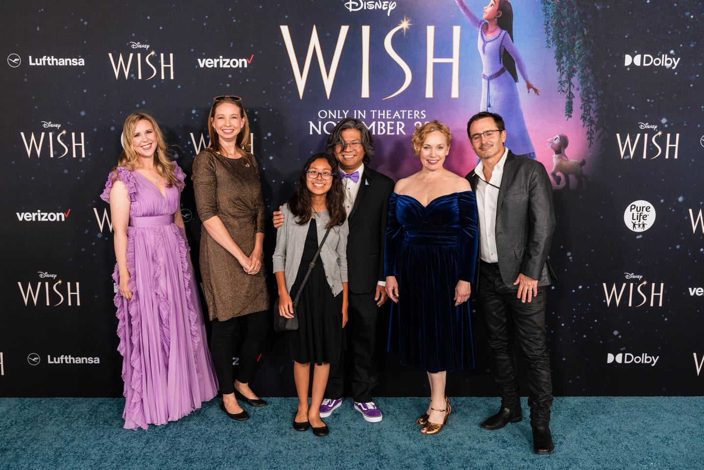 A group of guests on the blue carpet in front of the backdrop at the Disney Wish movie premiere in Hollywood