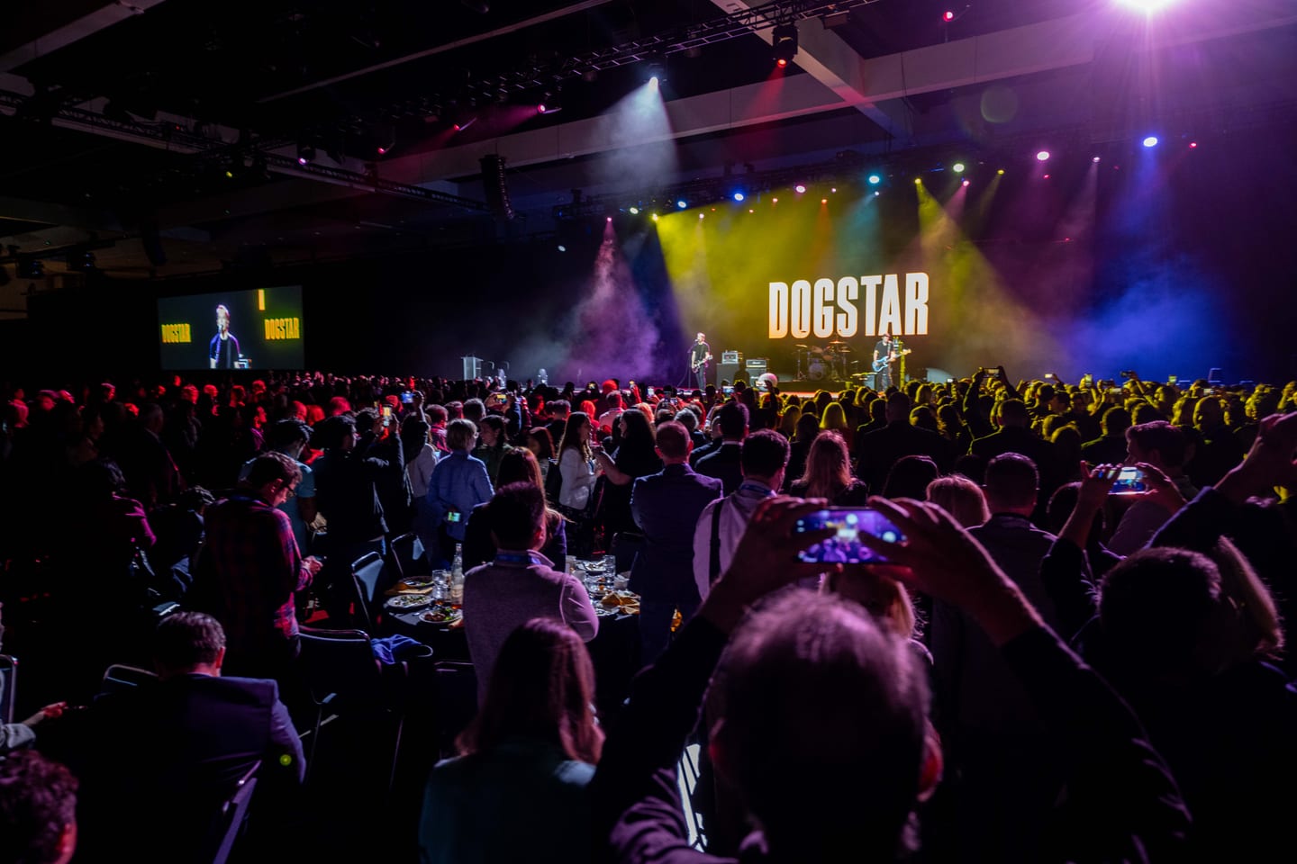 The band Dogstar performing on a wide lit stage before a standing crowd on IPW opening night