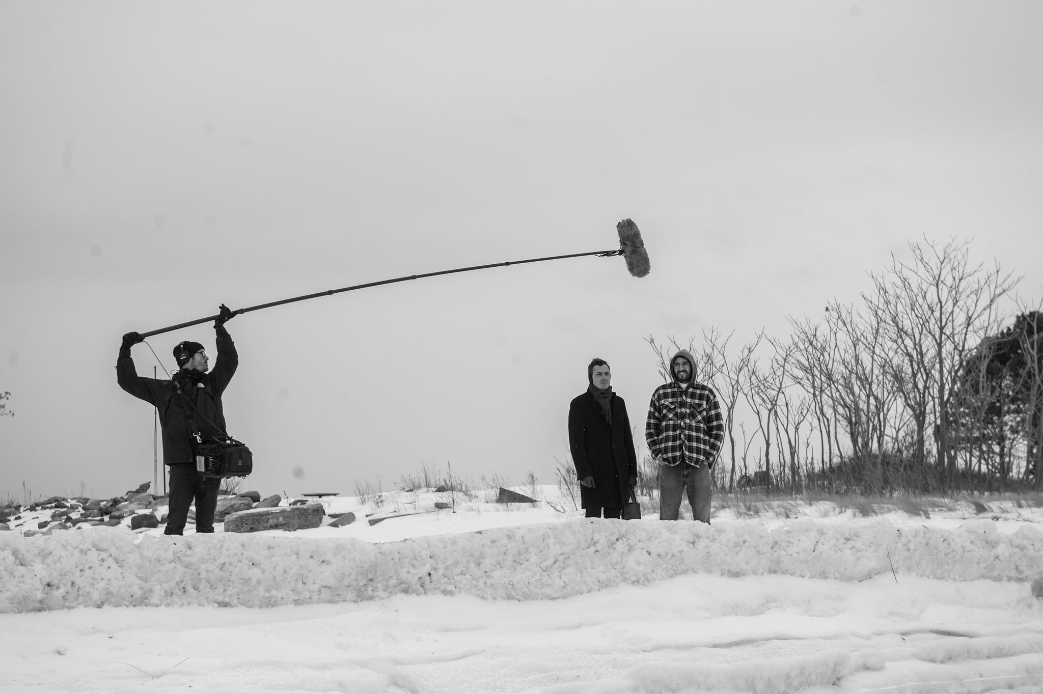 Black-and-white behind-the-scenes still from the indie film Donald Cried — a boom operator records two figures on a snowy landscape