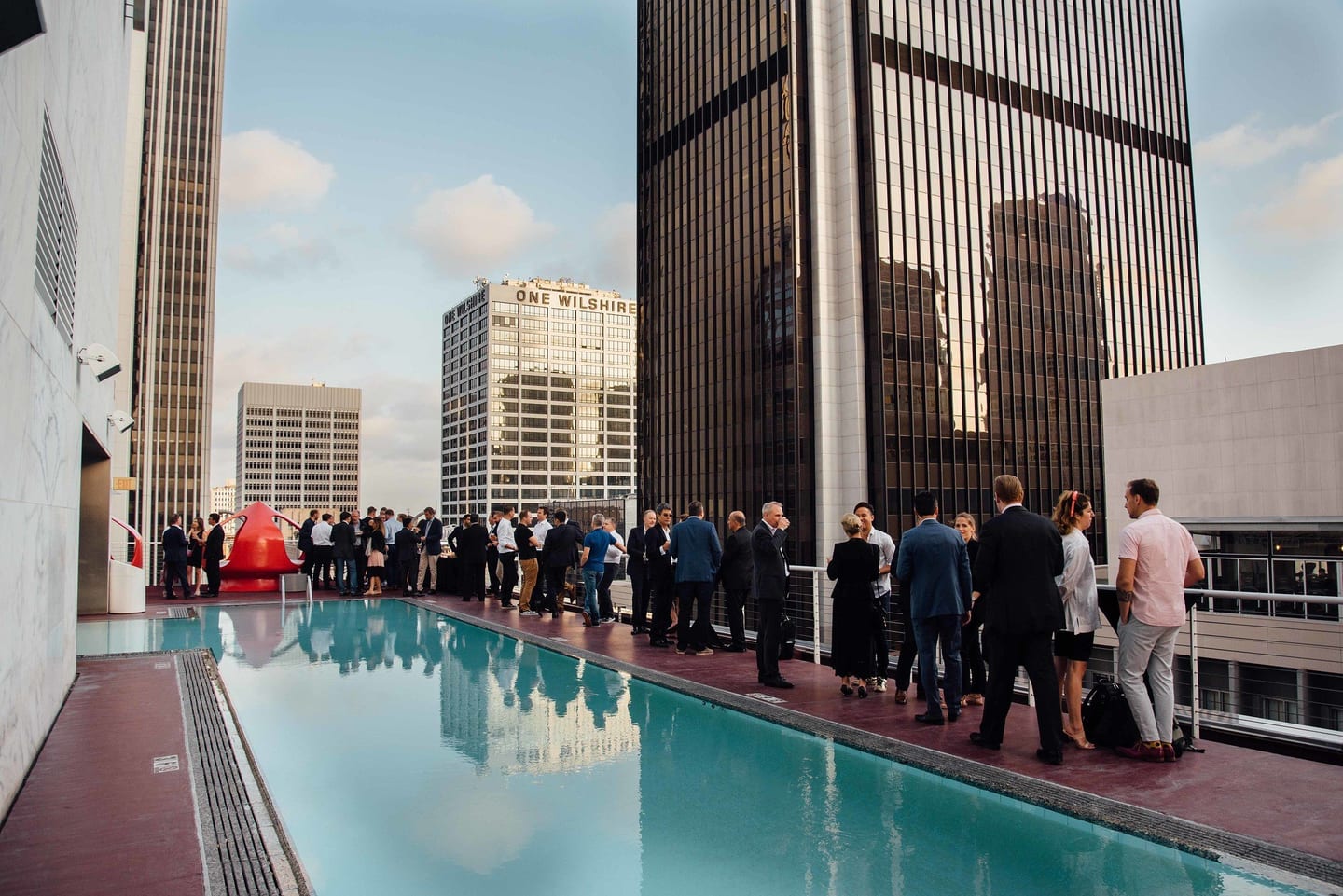 Guests at a rooftop pool deck reception between Downtown Los Angeles towers