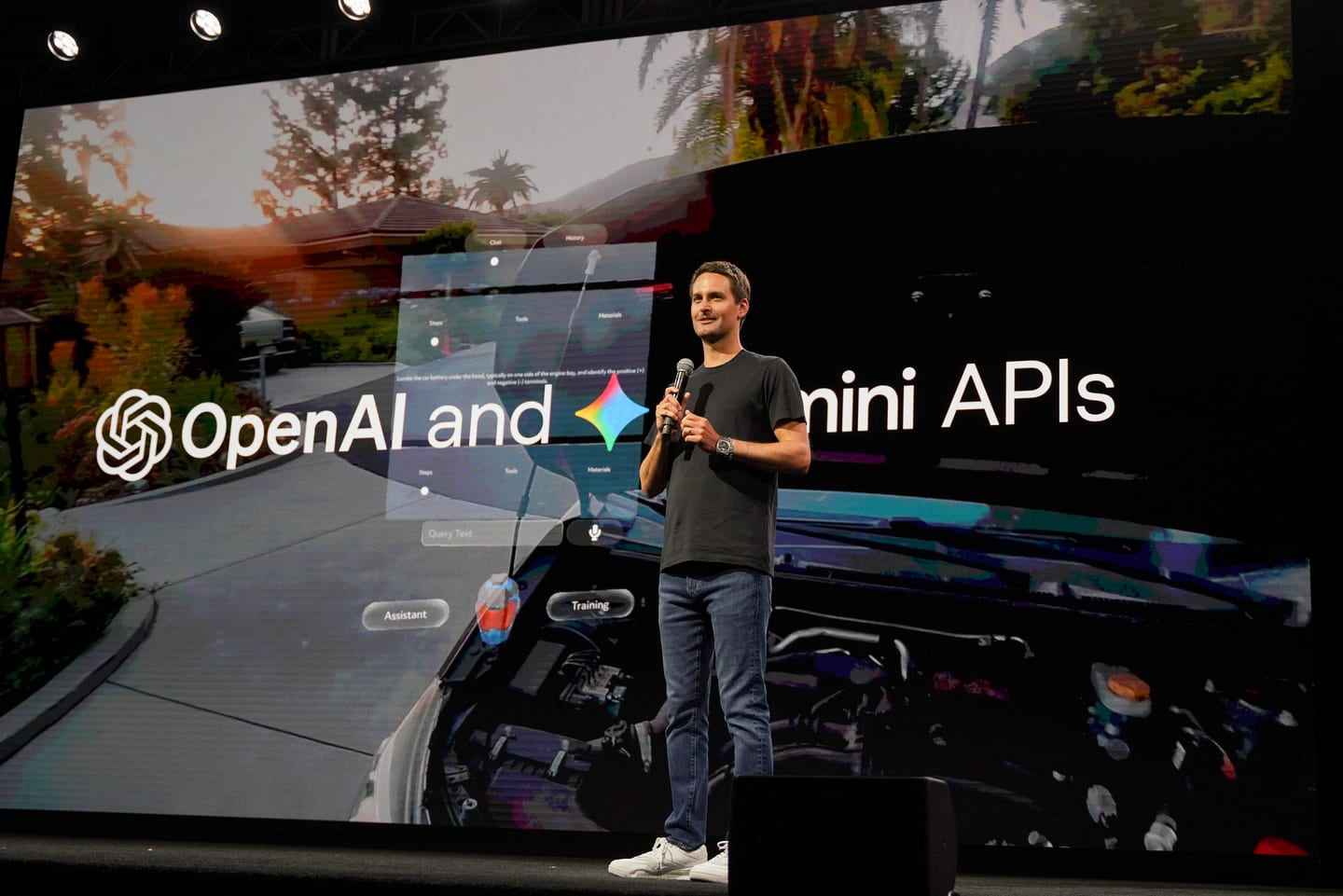 Snap CEO Evan Spiegel speaking on stage beside a large screen reading OpenAI and Gemini APIs at Augmented World Expo in Long Beach