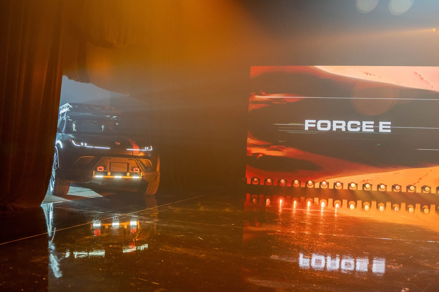 The Fisker Ocean Force E rolling offstage through fog beside the FORCE E screen