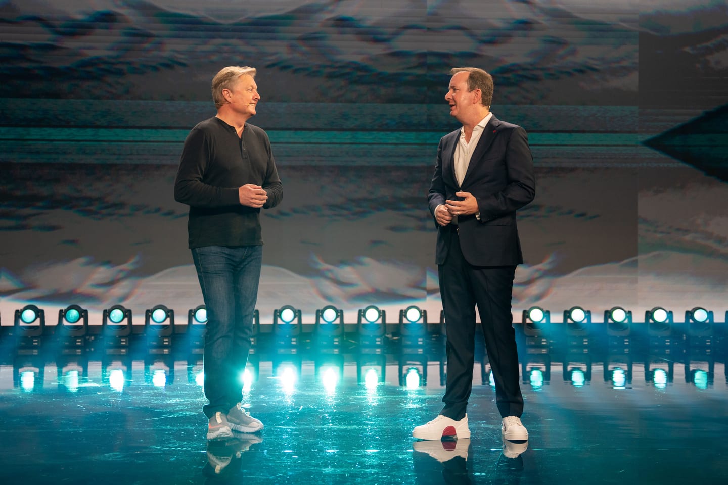 Two speakers together on the teal-lit stage