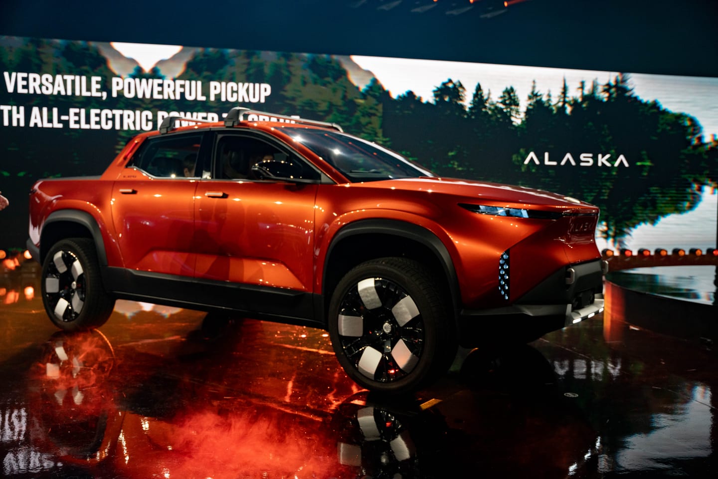The orange Fisker Alaska in profile beneath the Versatile, powerful pickup line on the ALASKA screen