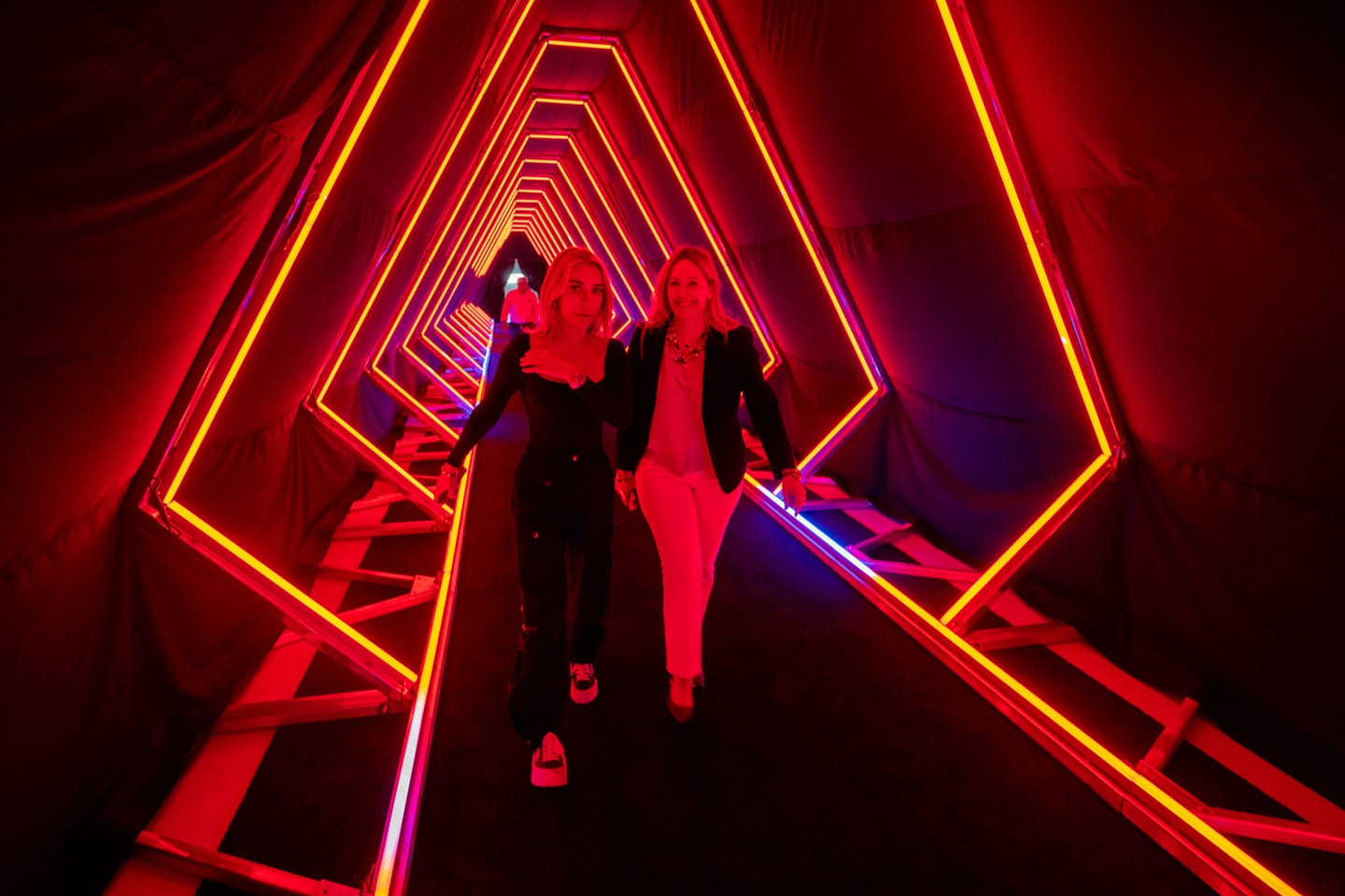 Two guests walking through the red neon tunnel activation