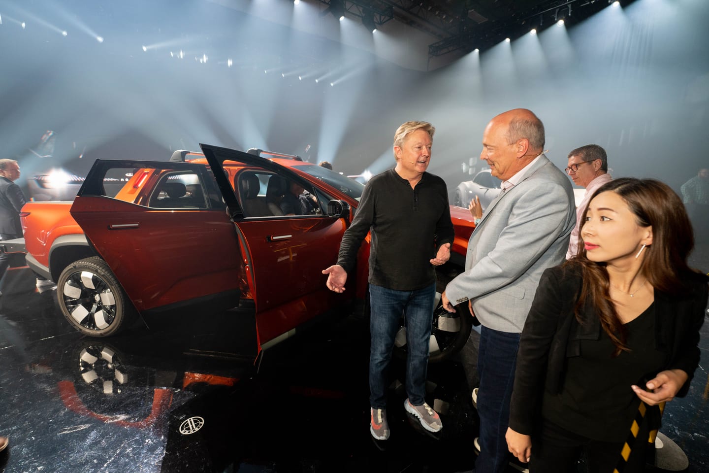 Guests at the open doors of the orange Fisker Alaska after the program