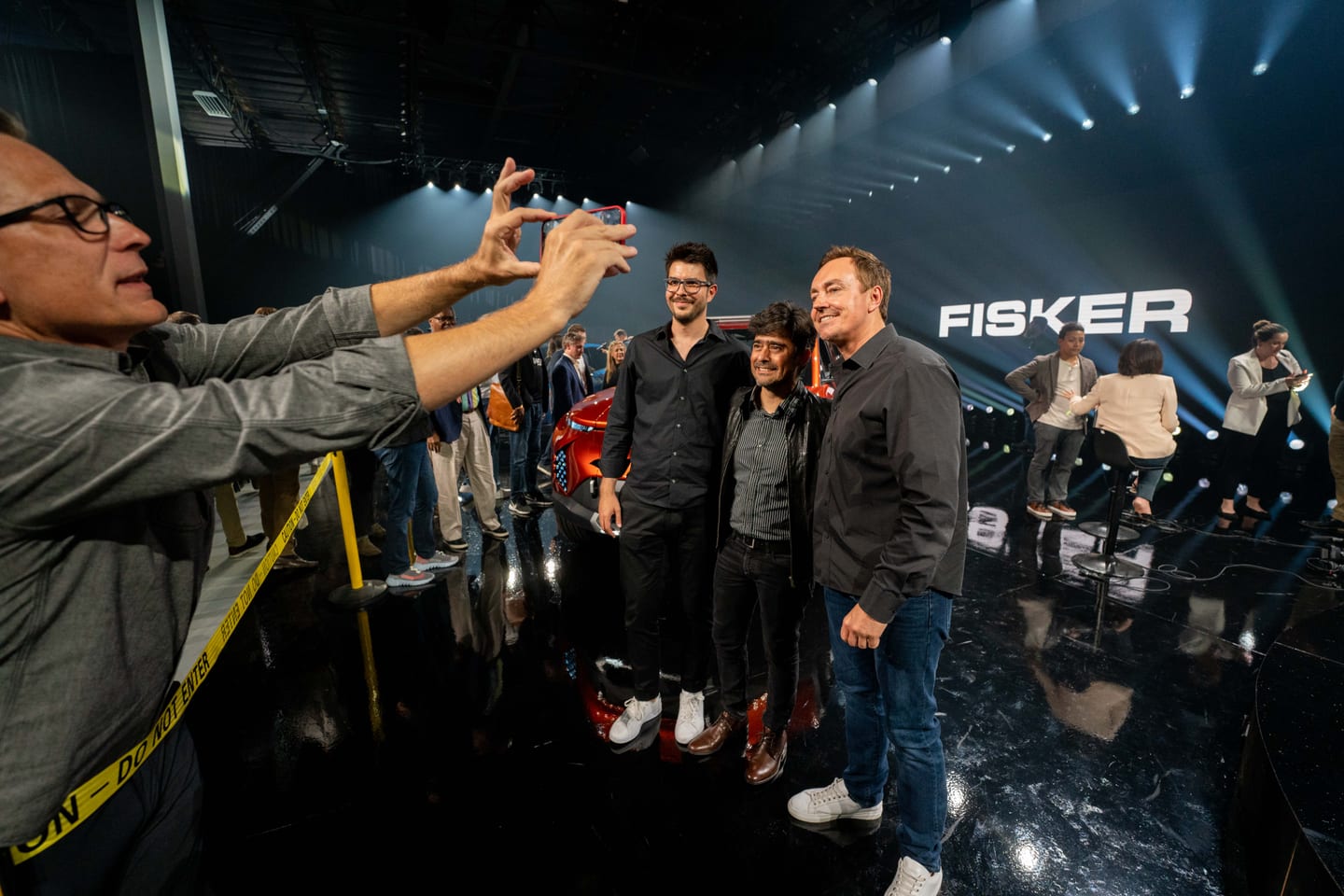 A group posing for a phone photo in front of the FISKER sign