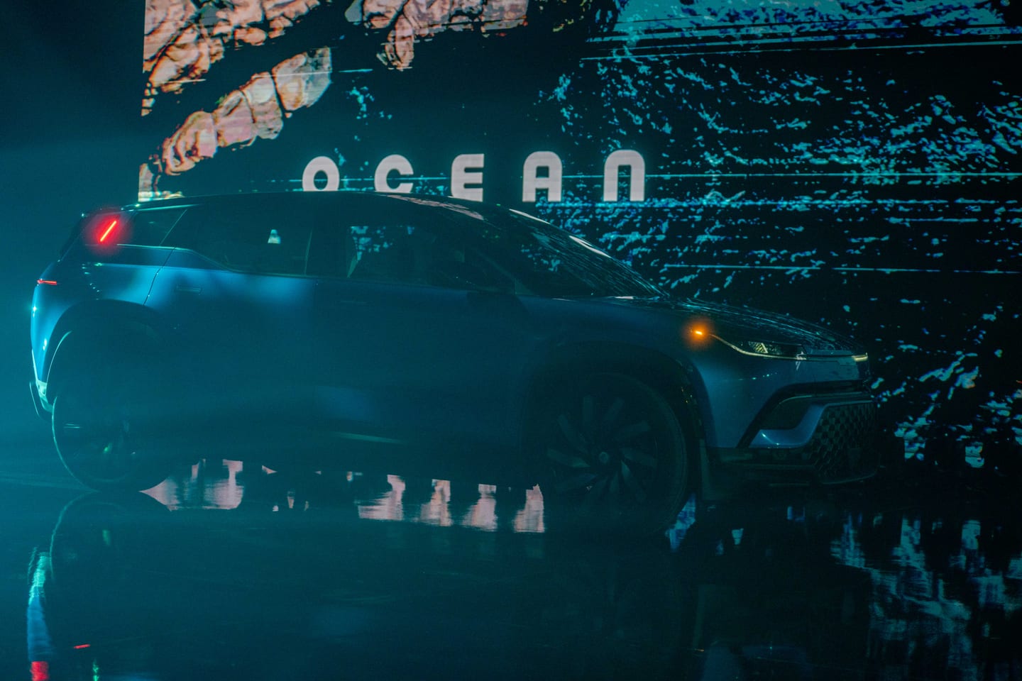 The Fisker Ocean in silhouette against the giant OCEAN screen