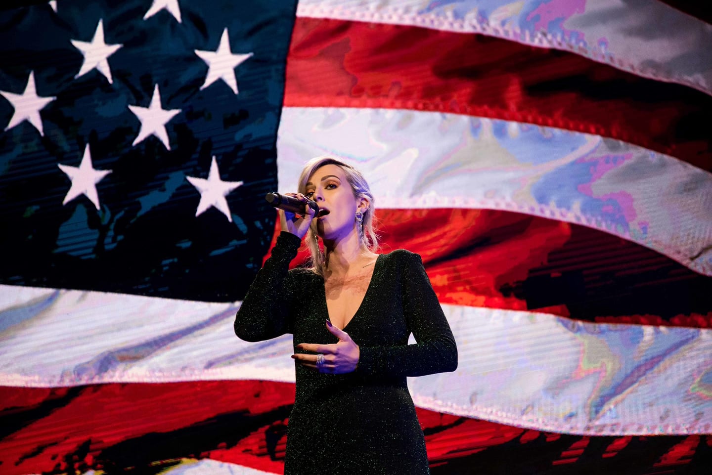 Singer performing in front of an American flag LED screen at a gala