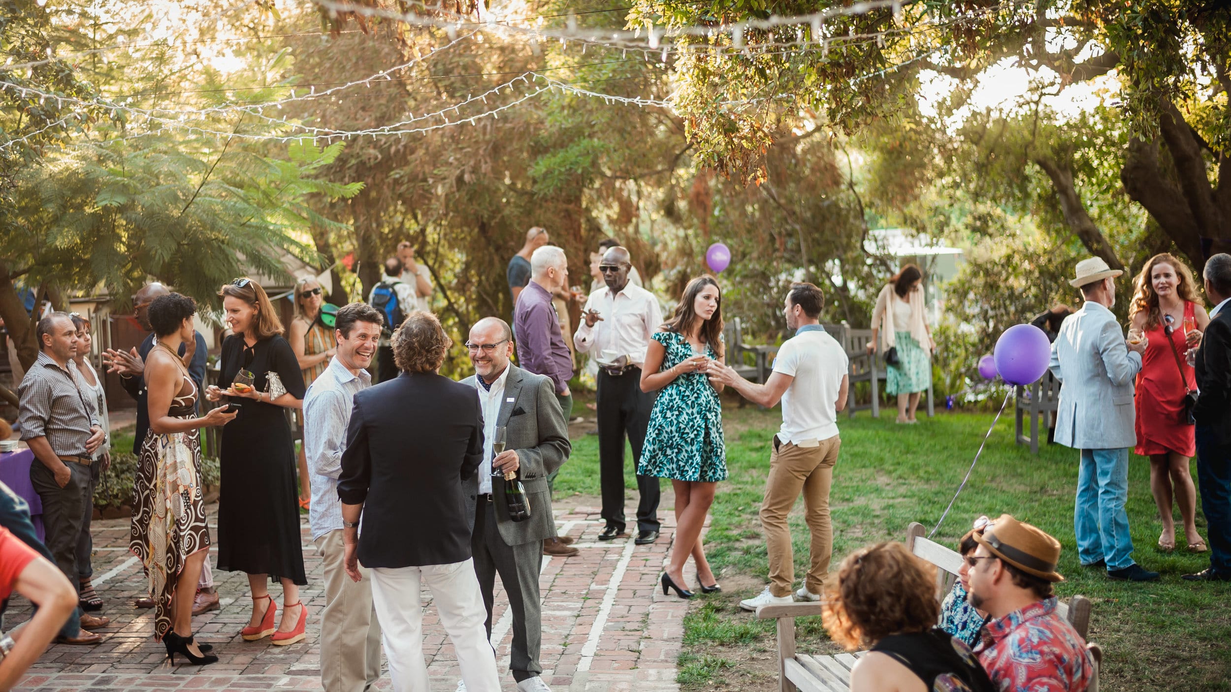 Guests mingling under the trees at an afternoon garden party