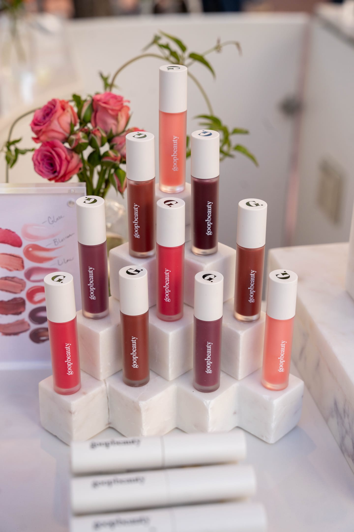 A display of goopbeauty lip products on a marble riser with pink roses at the goop pop-up in Pacific Palisades