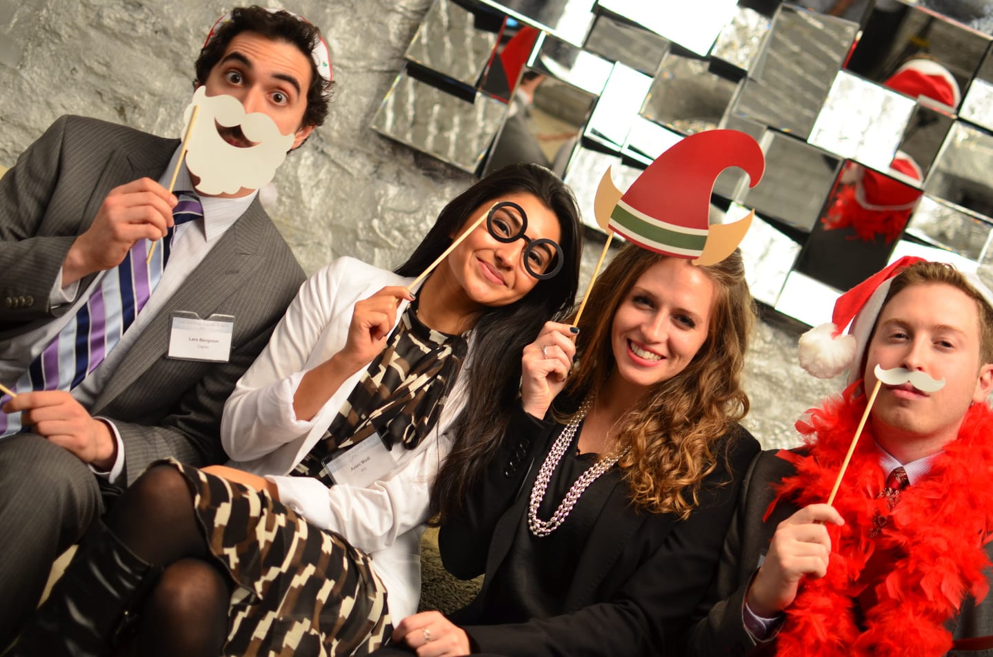 Guests posing with holiday photo-booth props at a company holiday party
