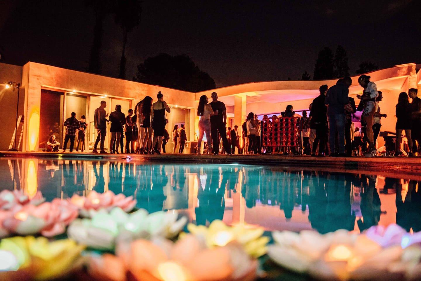 Wide view of guests around an estate pool with floating lanterns at a night party in the Hollywood Hills