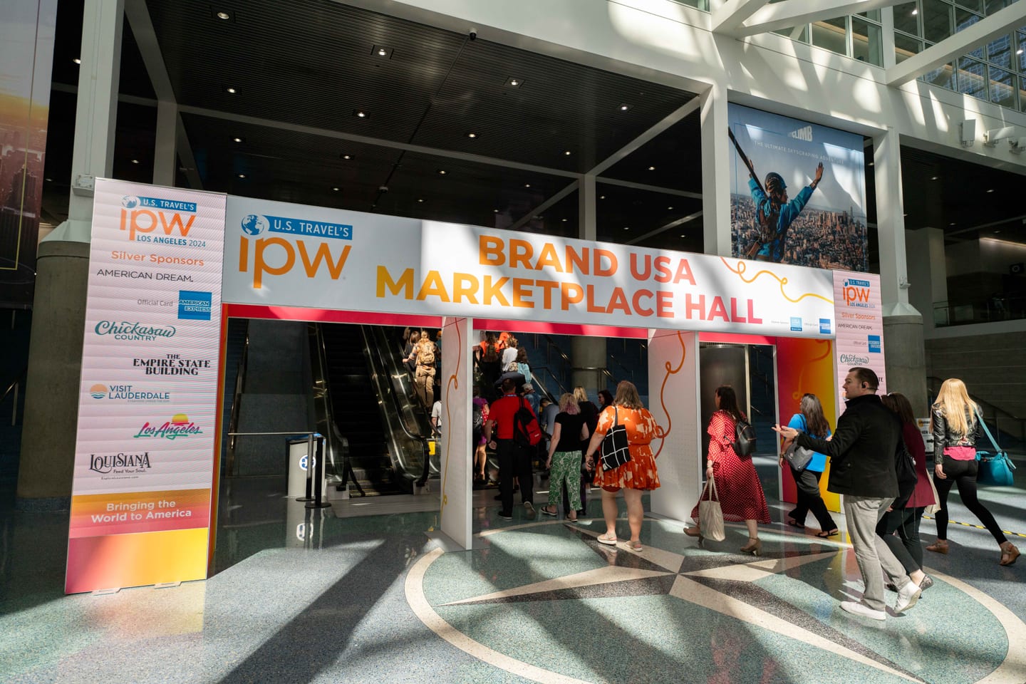 Delegates streaming through the Brand USA Marketplace Hall entrance at IPW beneath the IPW Los Angeles 2024 sign