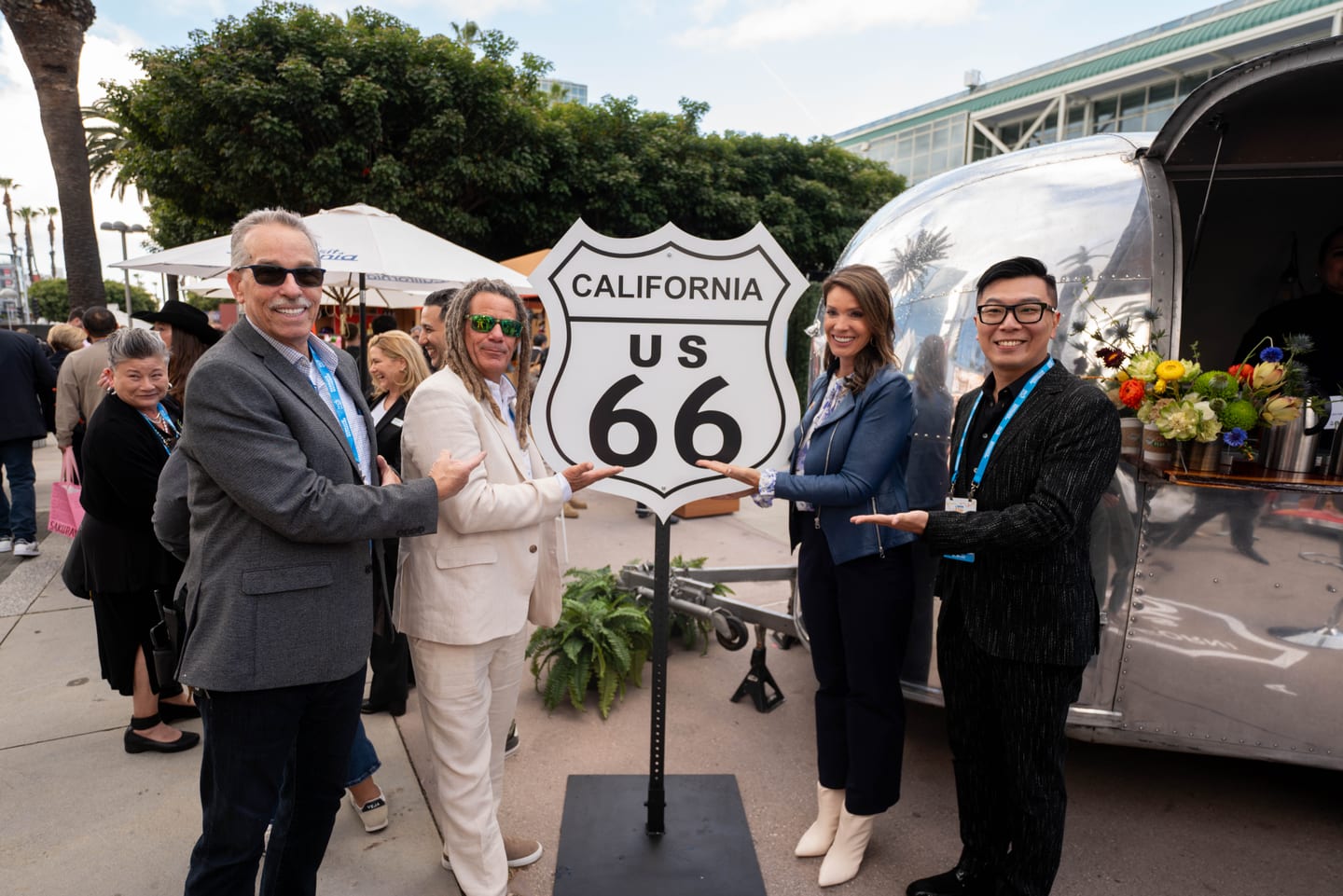 Guests posing beside a California Route 66 highway sign at an outdoor activation in IPW’s California Plaza