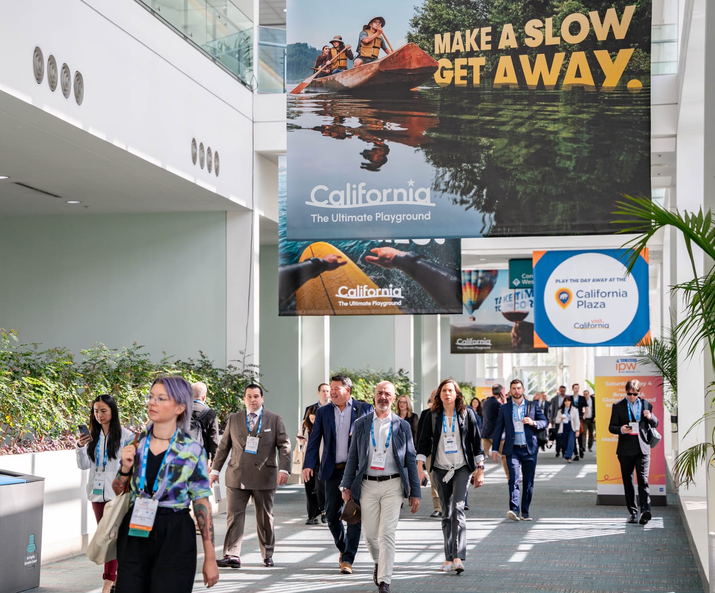 Delegates walking the Los Angeles Convention Center concourse past a California the Ultimate Playground display at IPW