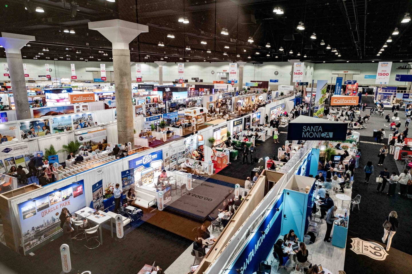 An overhead view of the IPW Marketplace floor with destination booths and string lights across the hall