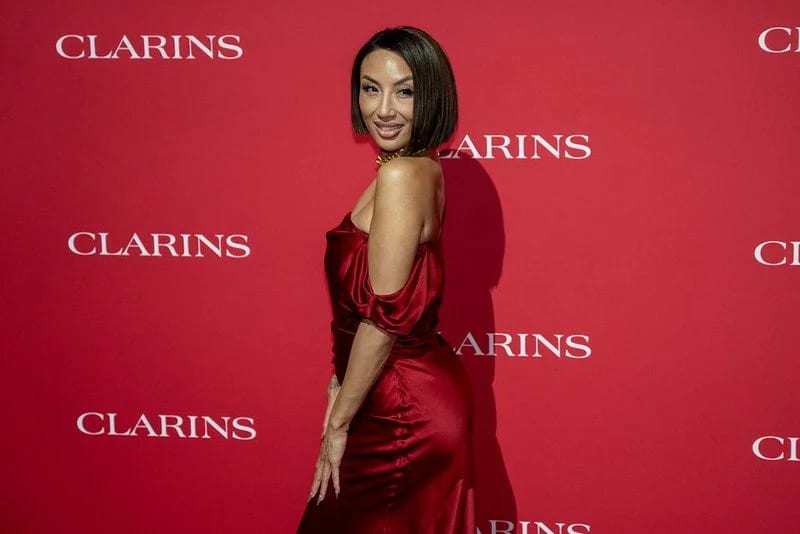 Jeannie Mai in a red satin dress on the Clarins Beauty Icons red carpet at the Academy Museum
