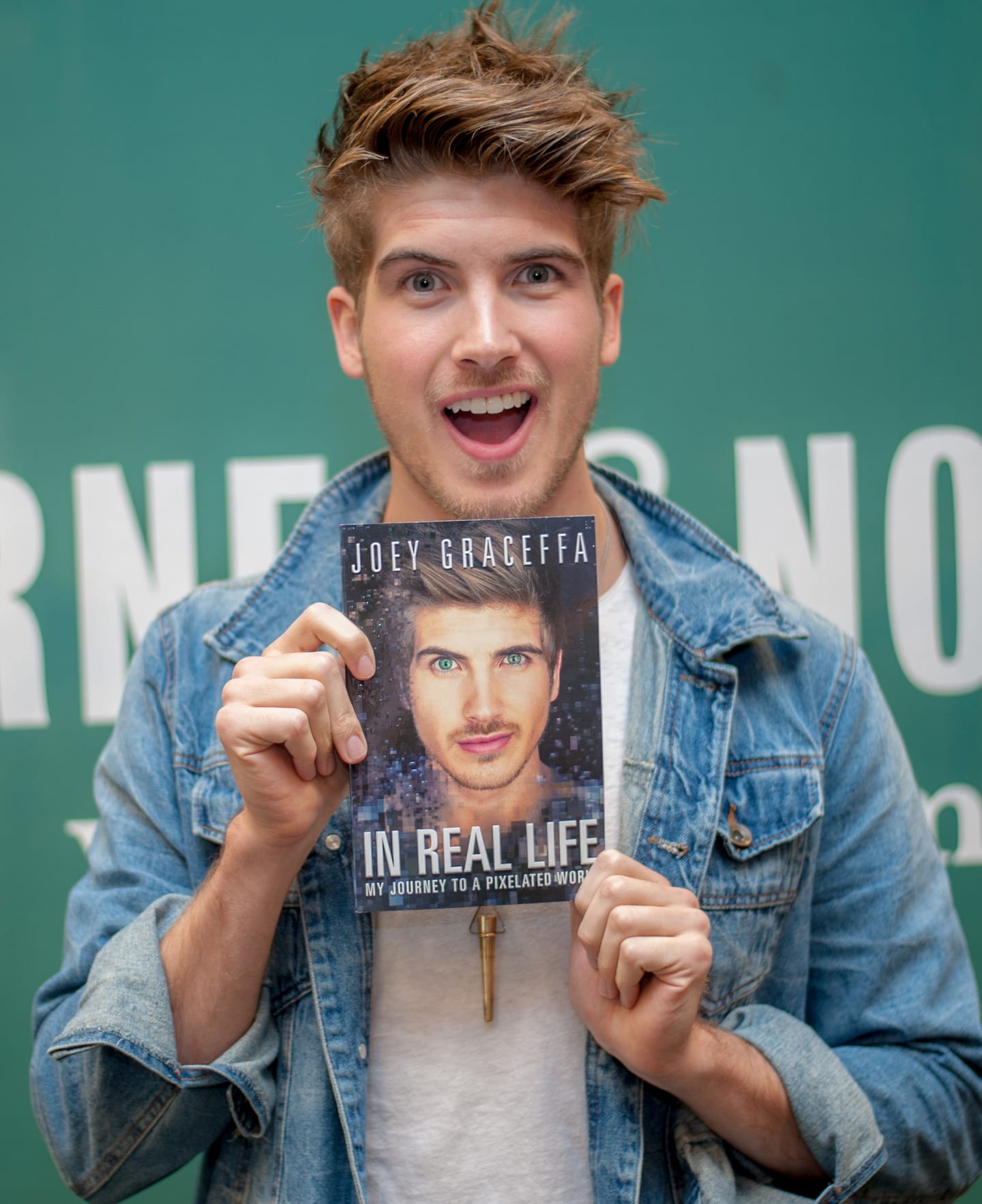 Joey Graceffa holding his memoir In Real Life at a Barnes and Noble book-signing event in Los Angeles