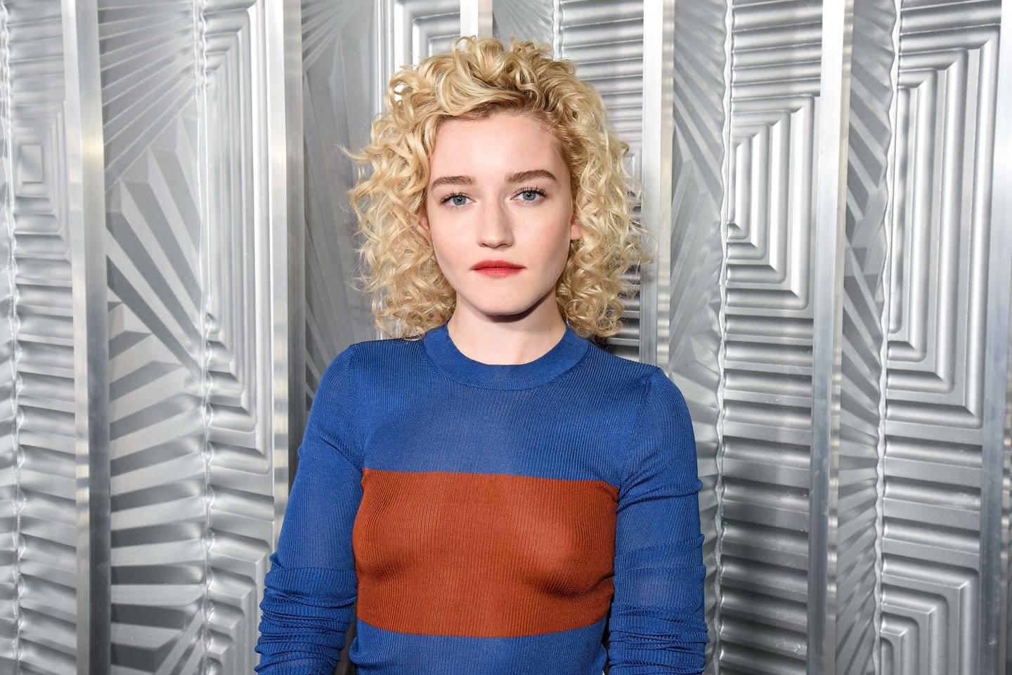 Julia Garner in a blue and rust dress against the silver Art Deco backdrop at ELLE Women in Hollywood