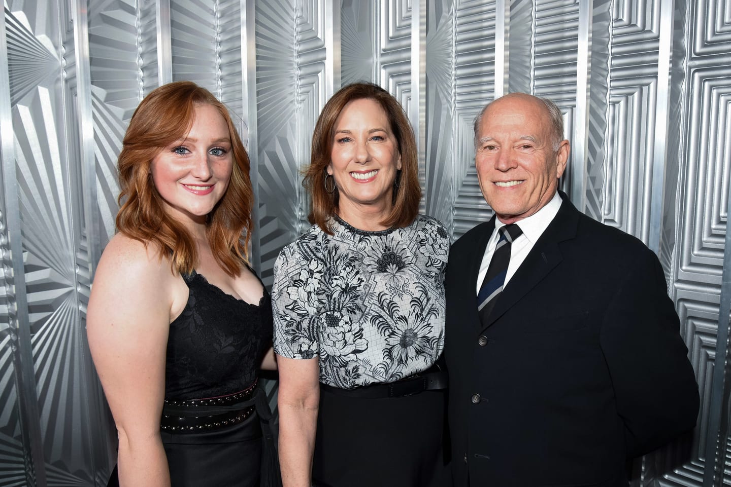 Producer Kathleen Kennedy and filmmaker Frank Marshall posing with a guest against the silver backdrop at ELLE Women in Hollywood