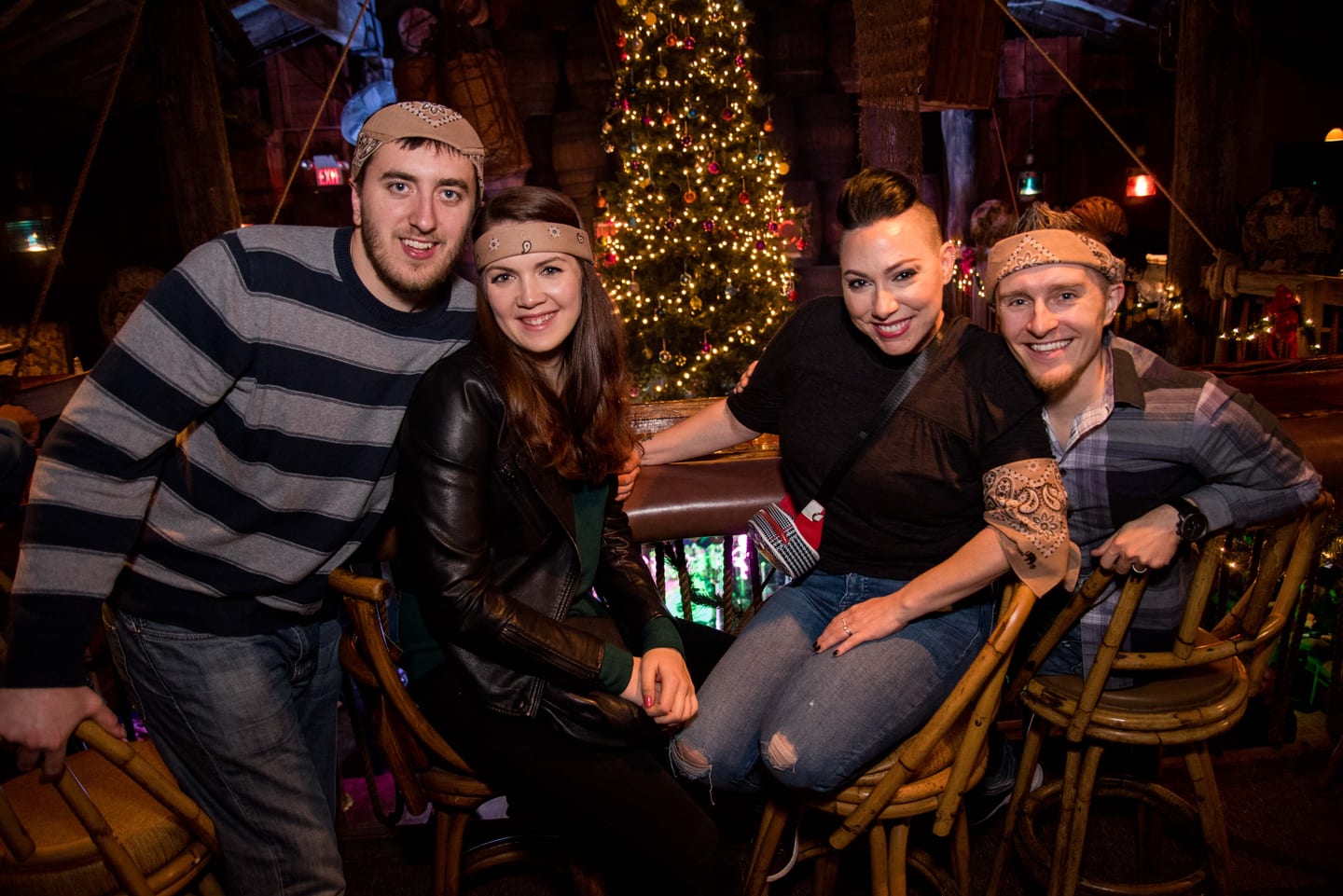 A group of guests in matching bandanas posing together in front of a Christmas tree at Niantic’s holiday party