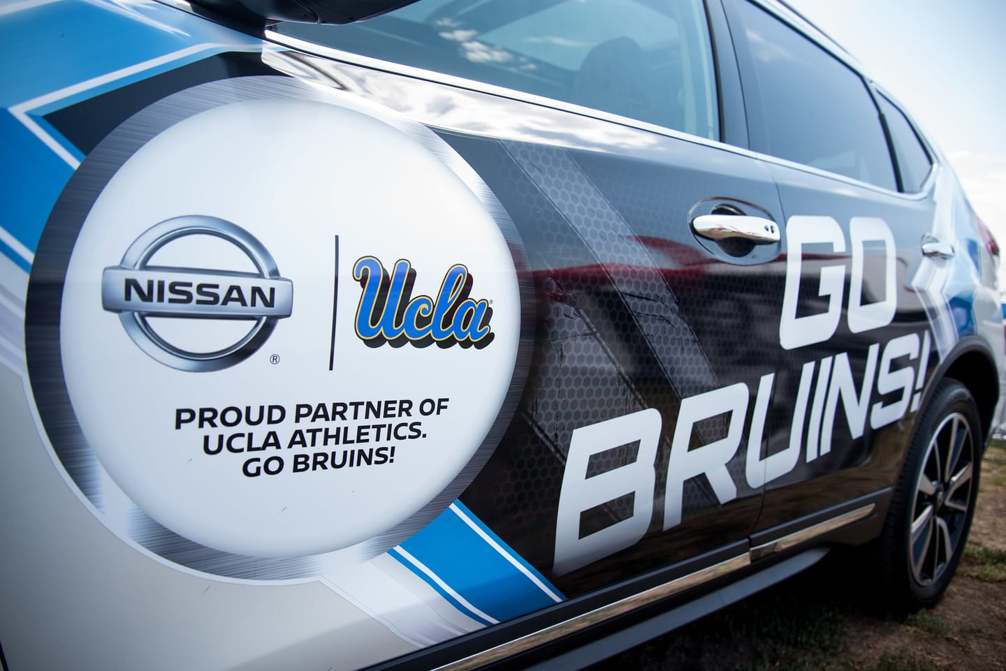 A Nissan vehicle wrapped in UCLA Athletics “Go Bruins” branding at a game-day brand activation in Los Angeles