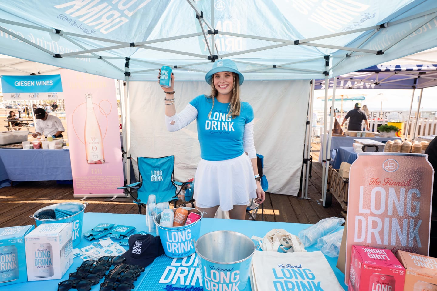 A brand ambassador holding a can at a Long Drink activation tent on the pier at the Off The Hook festival