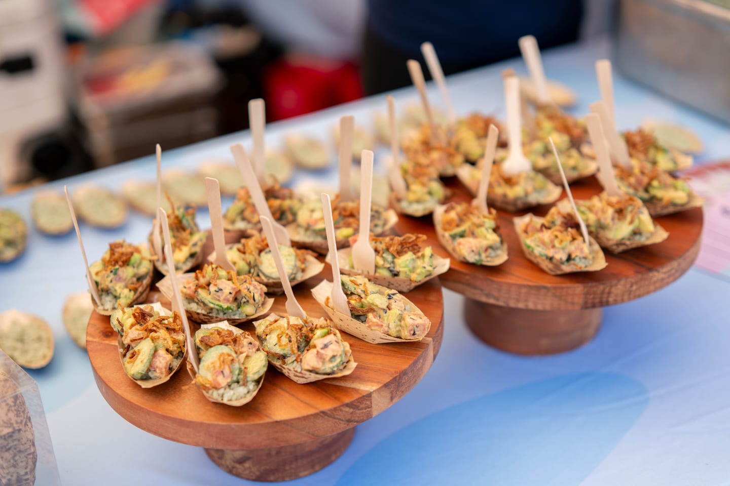 Wooden risers of poke tasting boats with tuna, avocado, and crispy shallots at the Off the Hook seafood festival on the Santa Monica Pier
