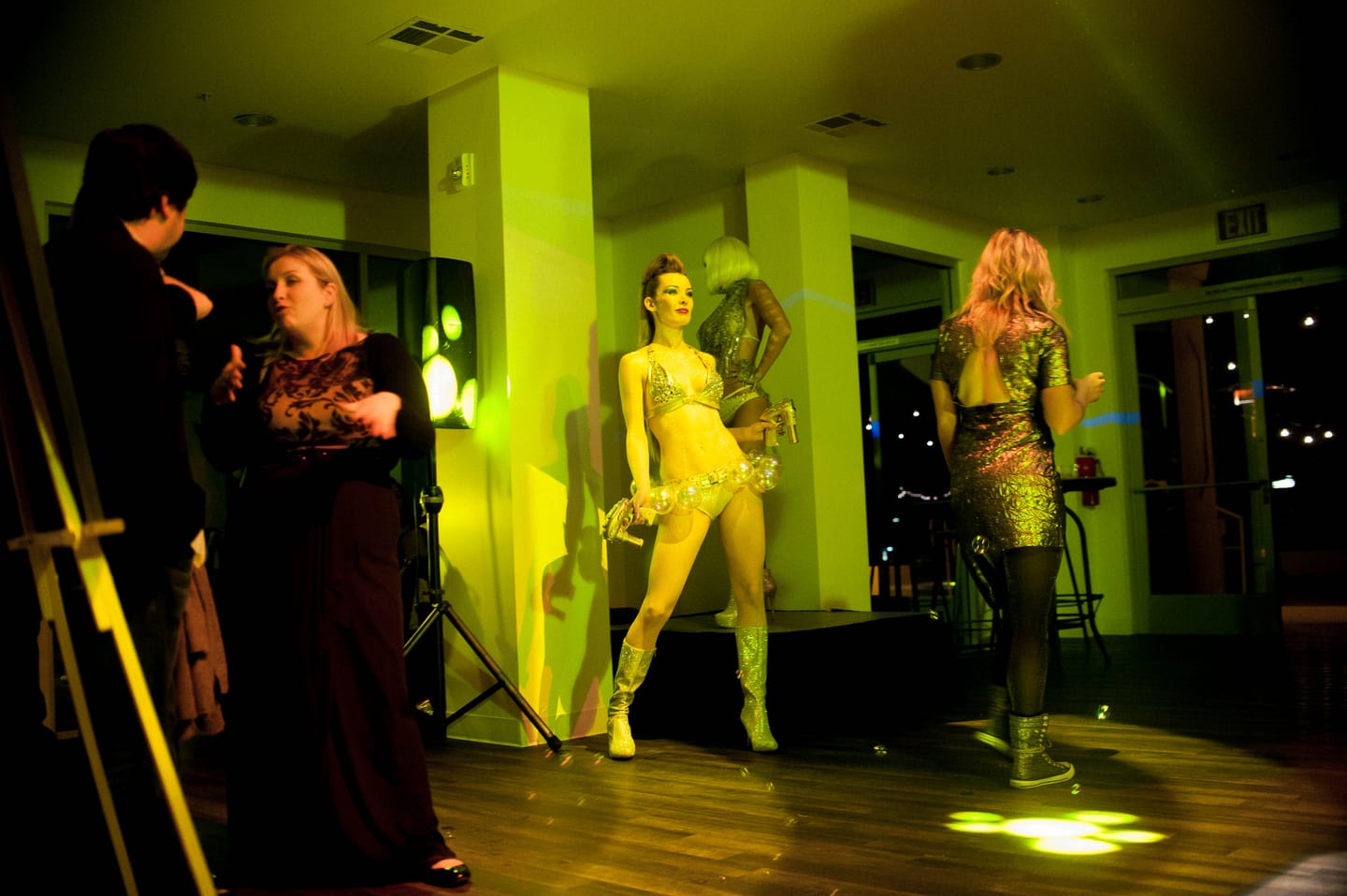Costumed performer in gold under green light entertaining guests at a private party