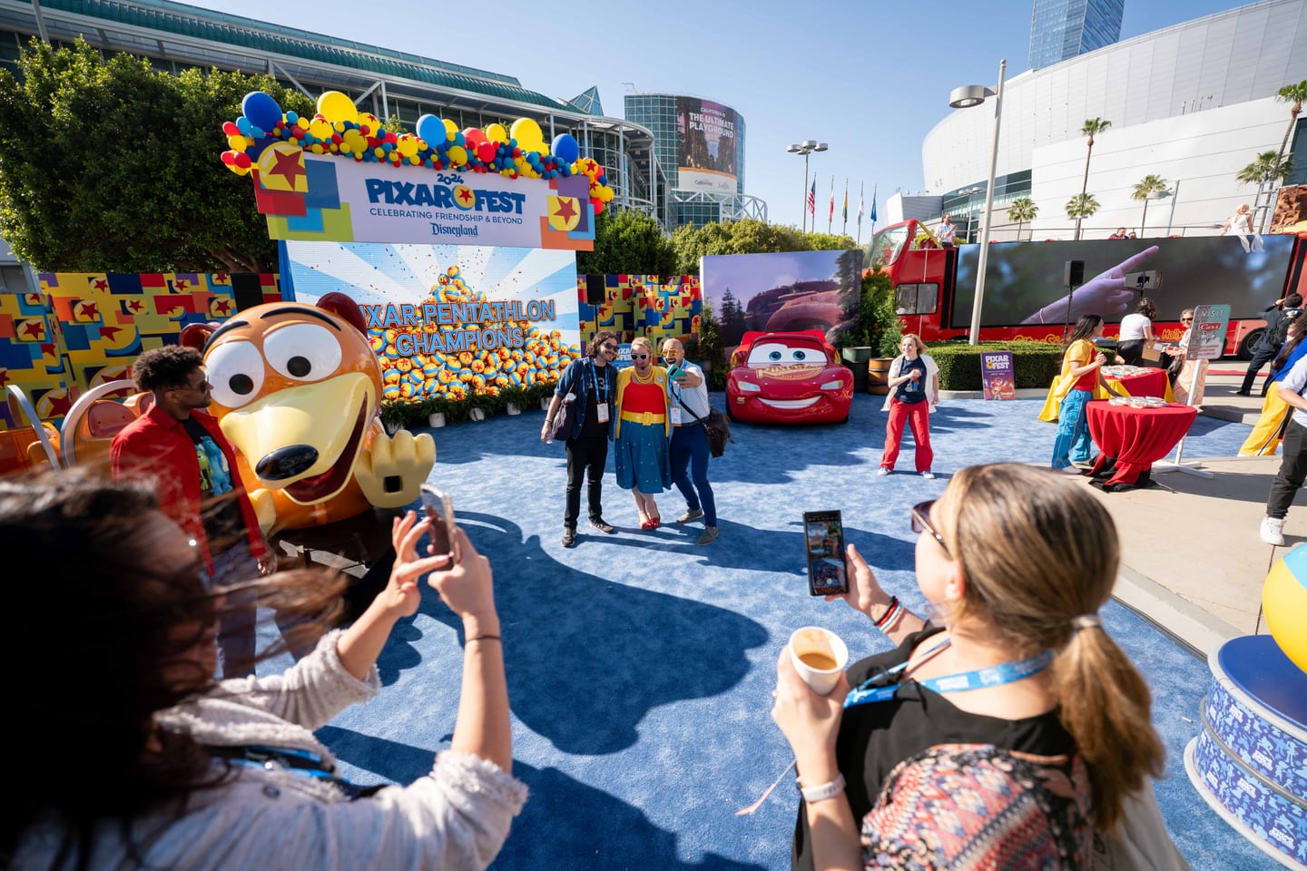 Delegates photographing Lightning McQueen and a Slinky Dog figure at Disneyland’s Pixar Fest activation outside the Los Angeles Convention Center
